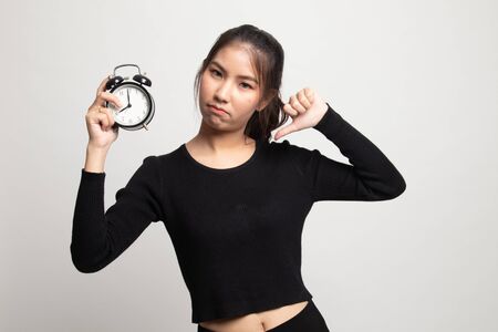 Young Asian woman thumbs down with a clock on white backgroundの写真素材