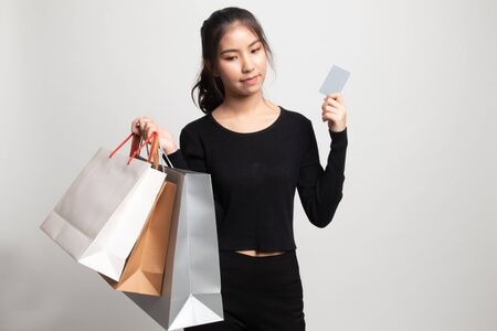 Young Asian woman with shopping bag and blank card on white backgroundの写真素材