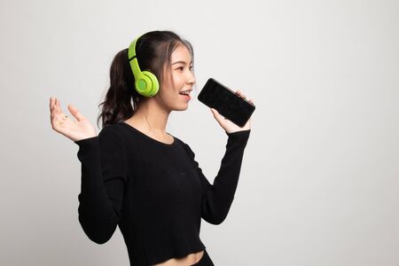 Pretty asian girl listening music with her headphones on white backgroundの写真素材