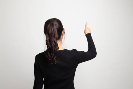 Back of Asian woman touching the screen with her finger on white backgroundの写真素材