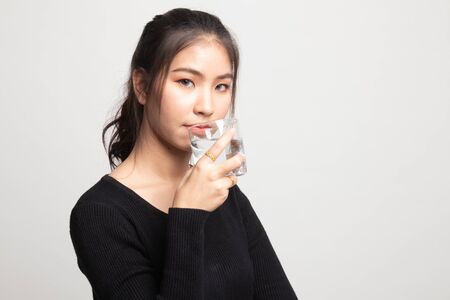 Young Asian woman with a glass of drinking water on white backgroundの写真素材