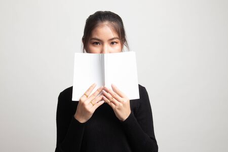 Young Asian woman with a book cover her face on white backgroundの写真素材