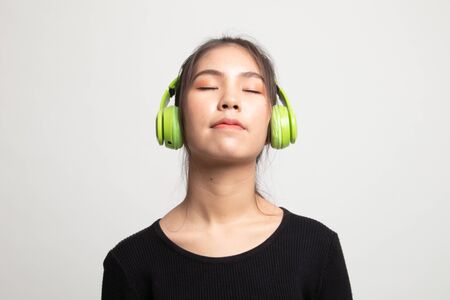 Pretty asian girl listening music with her headphones on white backgroundの写真素材