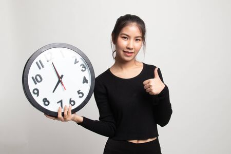 Young Asian woman thumbs up with a clock on white backgroundの写真素材