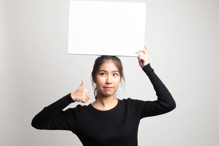 Young Asian woman show thumbs up with white blank sign on white backgroundの写真素材