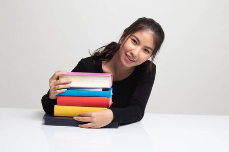 Happy young Asian woman read a book with books on table on white backgroundの写真素材