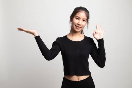 Beautiful young Asian woman show palm hand and OK sign on white backgroundの写真素材