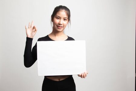 Young Asian woman show OK with white blank sign on white backgroundの写真素材