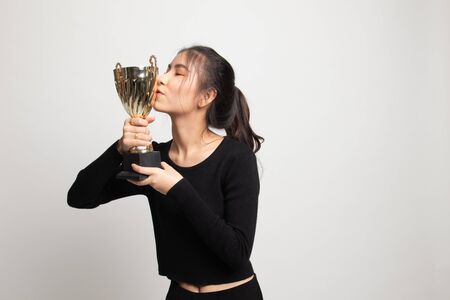 Successful young asian woman holding kissing a trophy on white backgroundの写真素材