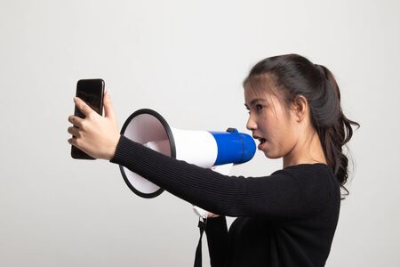 Angry  young Asian woman shout with megaphone to mobile phone on white backgroundの写真素材