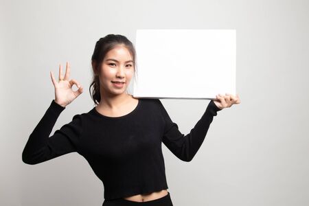Young Asian woman show OK with  white blank sign on white backgroundの写真素材