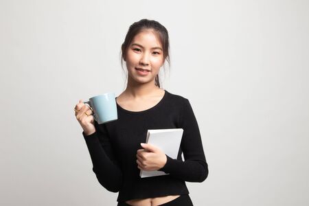 Young Asian woman with a book and cup of coffee on white backgroundの写真素材