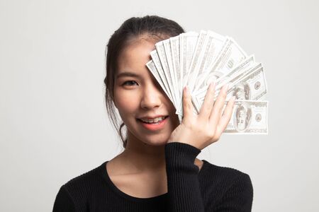 Portrait of  young asian woman  showing bunch of money banknotes on white backgroundの写真素材