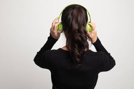 Pretty asian girl listening music with her headphones on white backgroundの写真素材