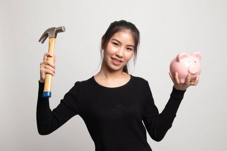 Asian woman with pig coin bank and hammer on white backgroundの写真素材