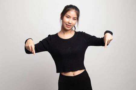 Beautiful young Asian woman point down to blank space on white backgroundの写真素材