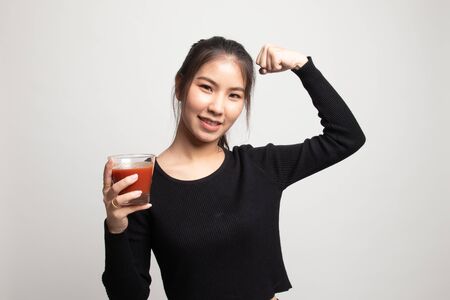 Strong healthy Asian woman with tomato juice on white backgroundの写真素材