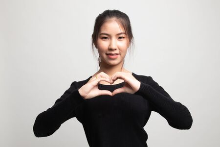 Young Asian woman show heart hand sign on white backgroundの写真素材