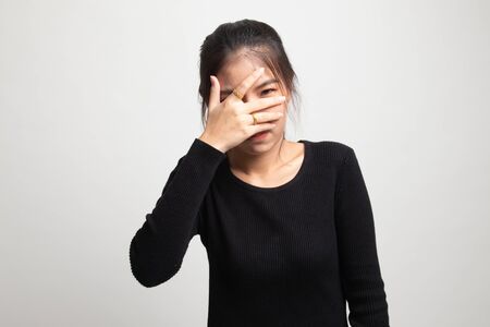 Beautiful young Asian woman peeking through fingers on white backgroundの写真素材