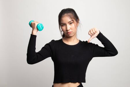 Unhappy Asian woman thumbs down with dumbbells on white backgroundの写真素材
