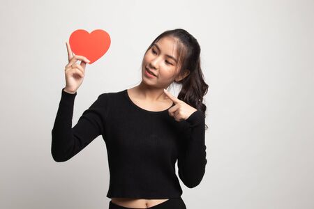 Asian woman point to red heart on white backgroundの写真素材