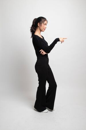 Full body side view of beautiful young asian woman pointing on white backgroundの写真素材