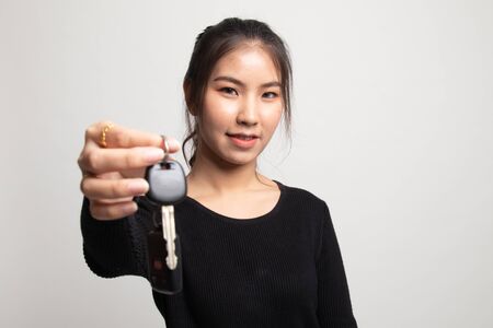 Cute asian girl showing home residence keys on white backgroundの写真素材