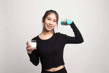 Healthy Asian woman drinking a glass of milk and dumbbell on white backgroundの写真素材