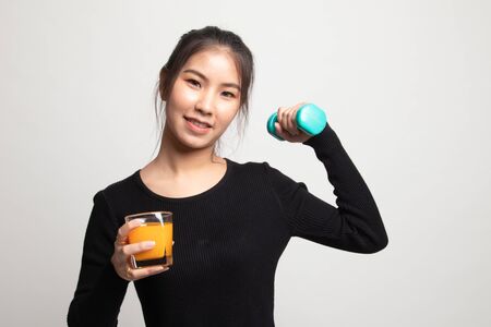 Young Asian woman with dumbbell drink orange juice on white backgroundの写真素材