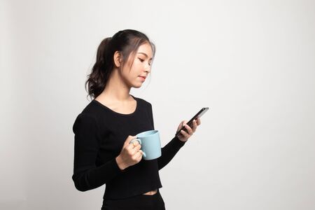 Young Asian woman with mobile phone and coffee cup on white backgroundの写真素材