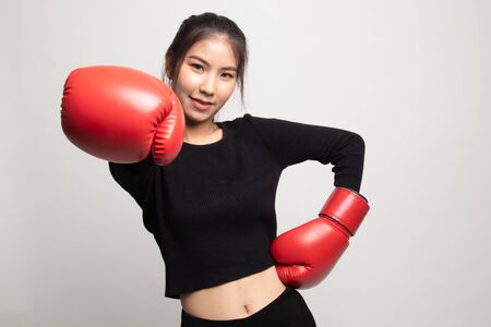 Young Asian woman with red boxing gloves on white backgroundの写真素材