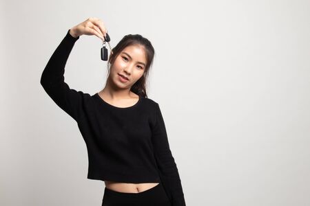 Cute asian girl showing home residence keys on white backgroundの写真素材