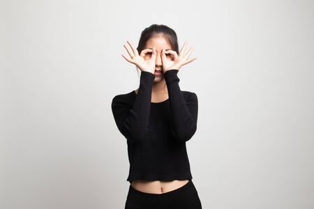 Asian woman do funny  double OK sign as glasses on white backgroundの写真素材