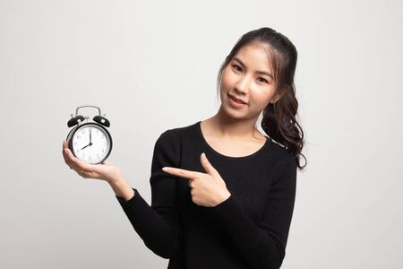Young Asian woman point to a clock on white backgroundの写真素材