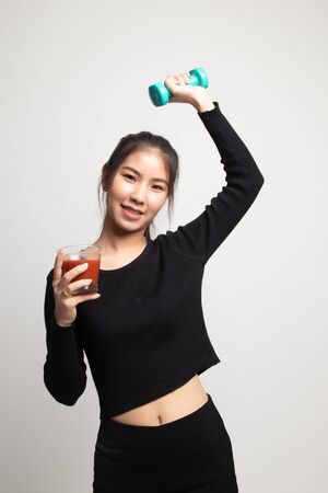 Young healthy Asian woman with dumbbell and  tomato juice on white backgroundの写真素材