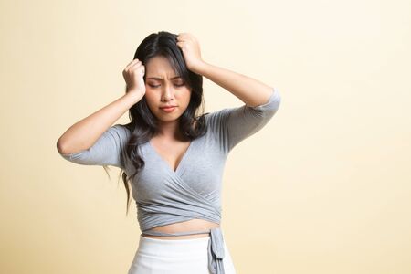 Young Asian woman got sick and  headache   on beige backgroundの写真素材