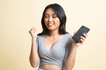 Happy Young Asian woman with mobile phone   on beige backgroundの写真素材