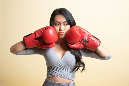 Young Asian woman with red boxing gloves   on beige backgroundの写真素材