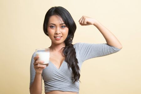Healthy Asian woman drinking a glass of milk   on beige backgroundの写真素材