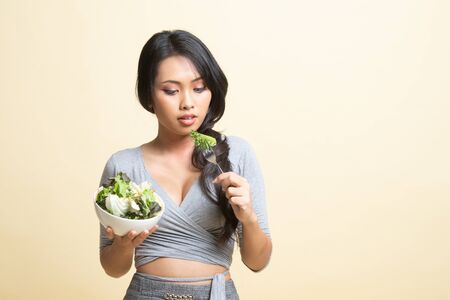 Healthy Asian woman with salad   on beige background