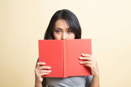 Young Asian woman with a book cover her face   on beige backgroundの写真素材