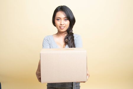 Delivery, relocation and unpacking.  young asian woman holding cardboard box   on beige background