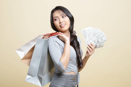Portrait of  young asian woman  showing bunch of money banknotes   on beige backgroundの写真素材