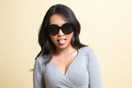 Portrait of a beautiful young asian girl in sunglasses   on beige backgroundの写真素材