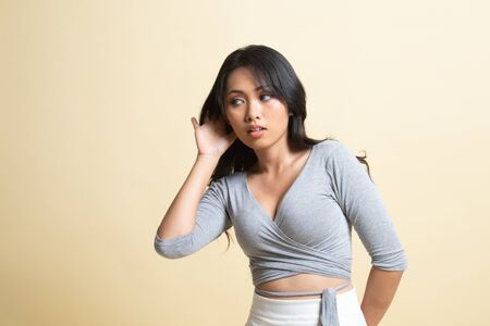 Beautiful young Asian woman listen to something   on beige backgroundの写真素材