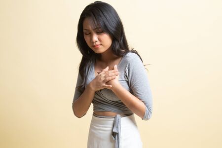 Young Asian woman got chest pain   on beige backgroundの写真素材