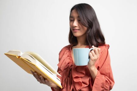 Young Asian woman with a book and cup of coffee on white backgroundの写真素材