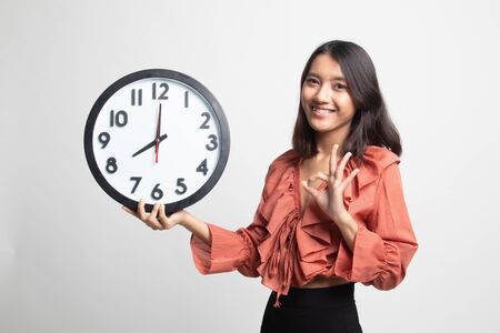Young Asian woman show OK with a clock on white backgroundの写真素材