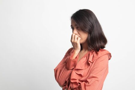 Unsure hesitant nervous young asian  woman biting her fingernails on white backgroundの写真素材