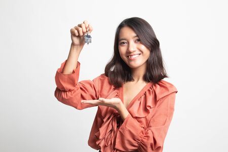 Cute asian girl showing home residence keys on white backgroundの写真素材